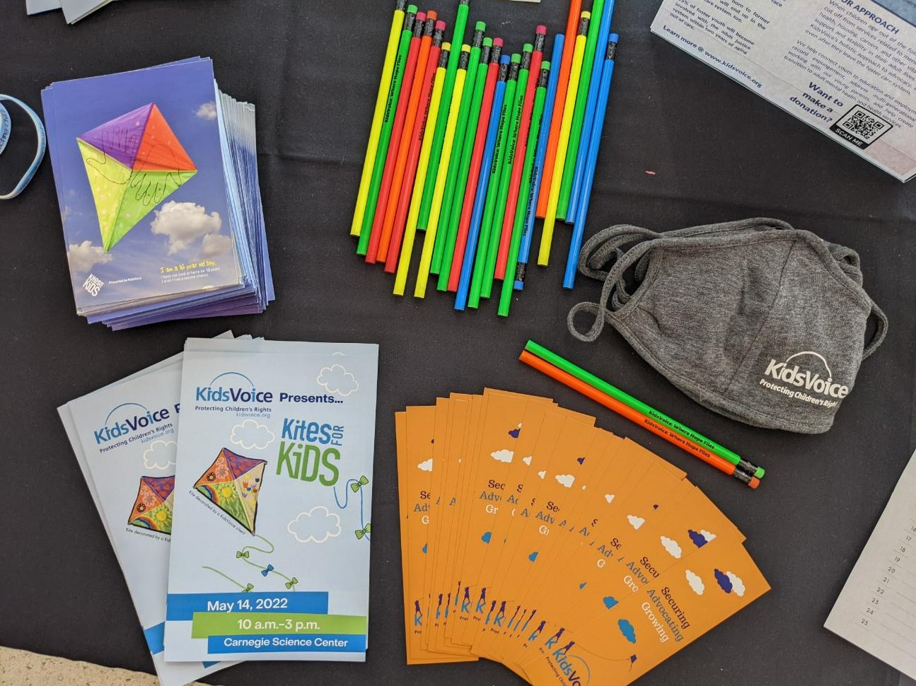 A display of KidsVoice branded supplies, including colorful pencils, facial masks, and bright orange bookmarks