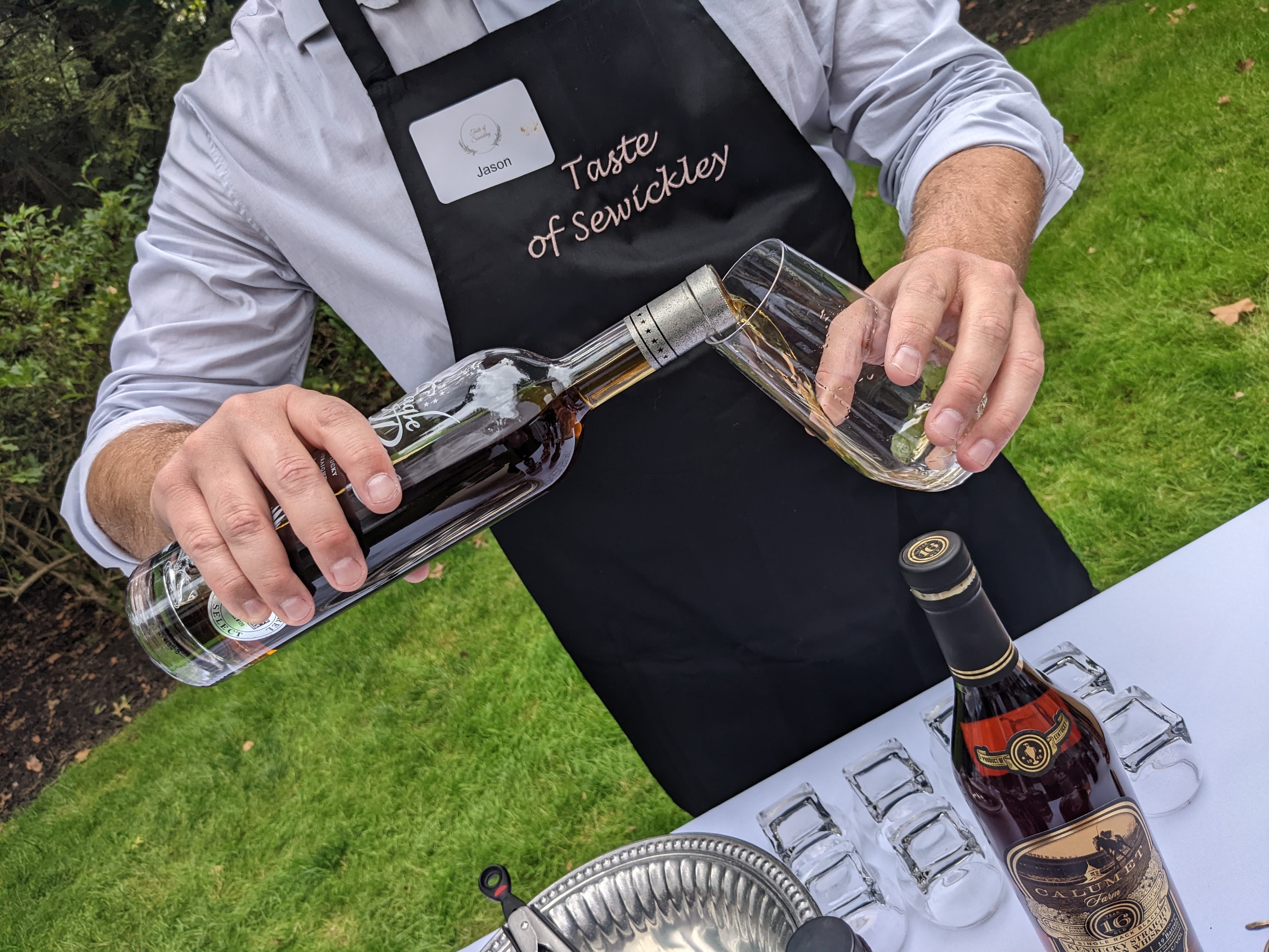 A man in a Taste of Sewickley apron pours a drink